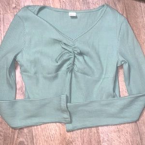A light green top with a ribbon tied in the middle. Long sleeve top.